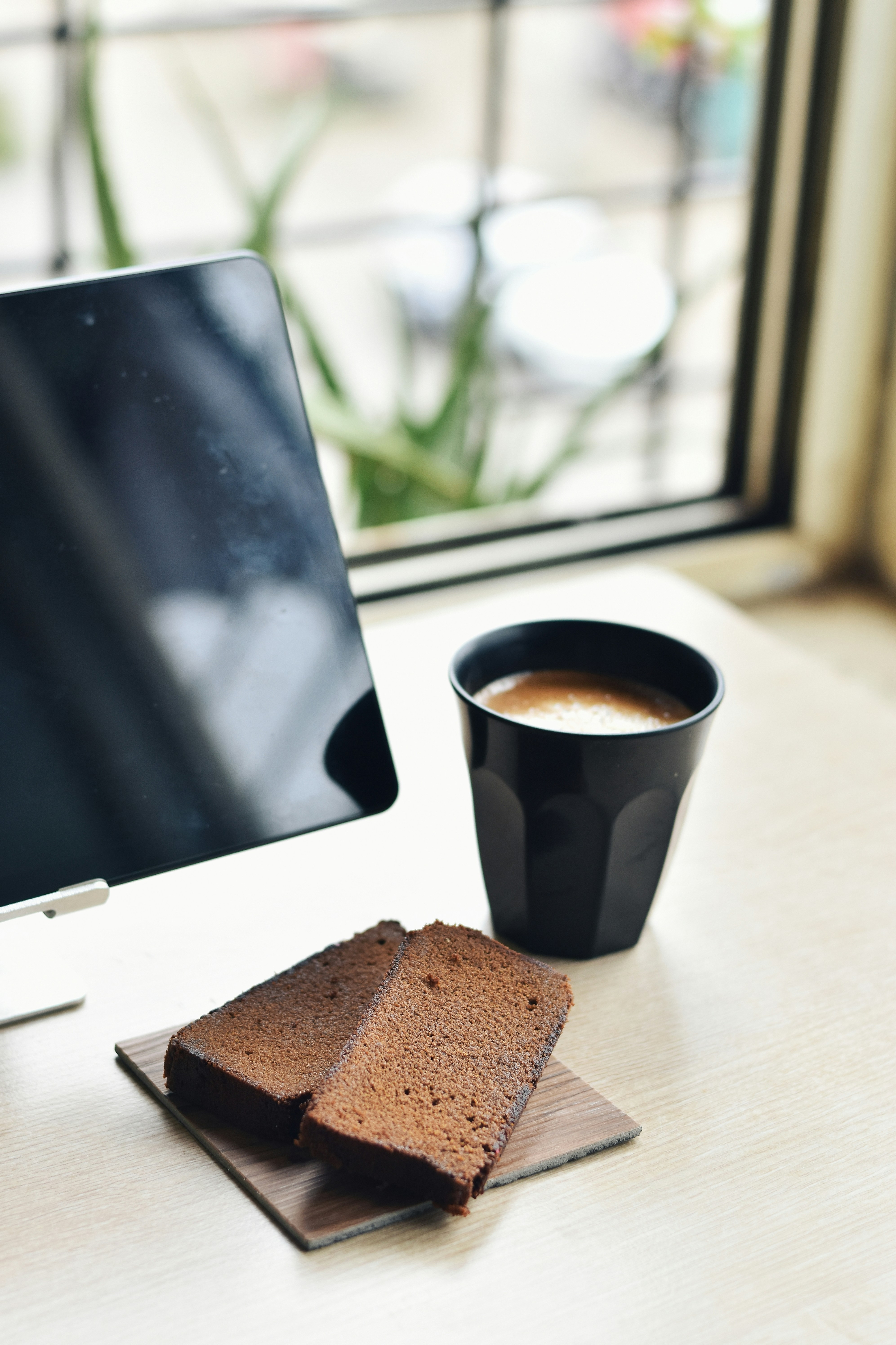 eine Tasse Kaffee und ein Stück Kuchen auf dem Schreibtisch