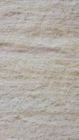Close-up of creamy travertine with natural pits and textured surface.