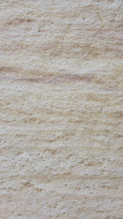 Close-up of creamy travertine with natural pits and textured surface.