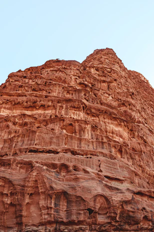 A close-up of a drilling rig’s drill bit cutting through rock layers under a clear blue sky.