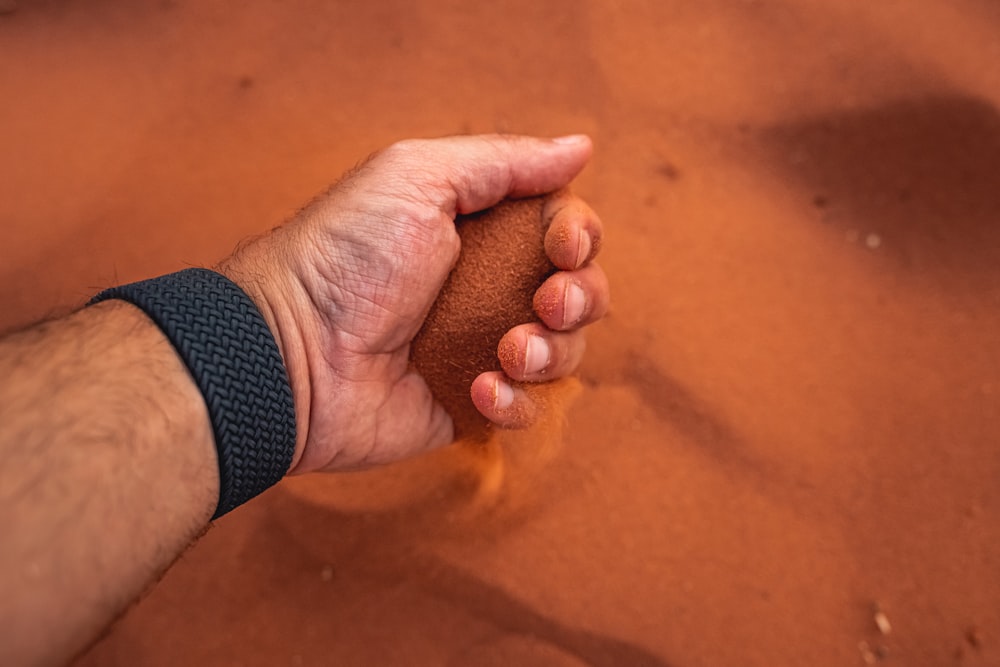 a hand holding a sand dune in the desert