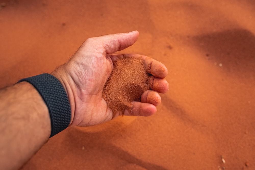 a hand holding sand in the middle of a desert