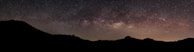 A panoramic view of the Milky Way over a mountain range.