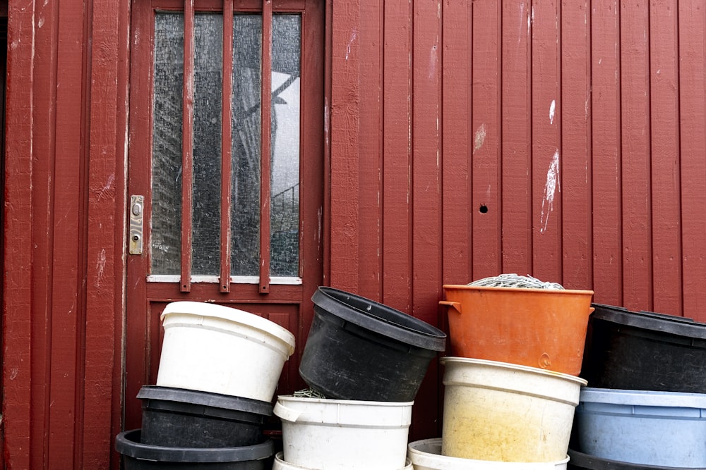 a pile of buckets sitting in front of a red building