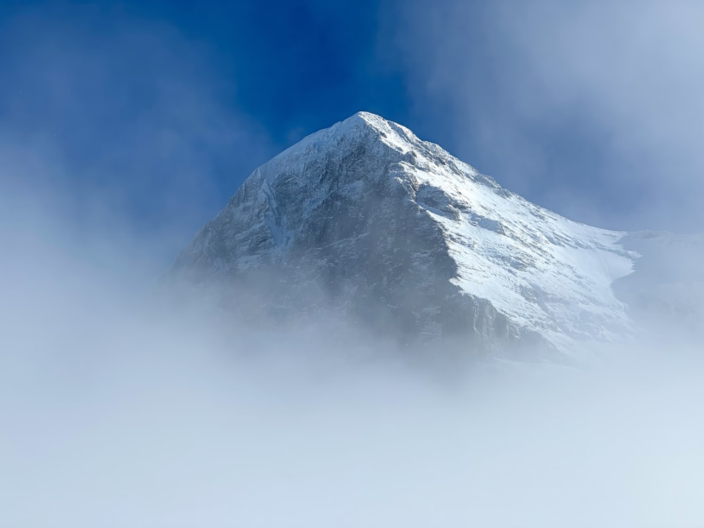 a snow covered mountain in the middle of a cloud filled sky