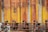 A row of industrial storage tanks with peeling and rusted yellow paint. The tanks are numbered from one to five and have corroded pipes running along the bottom. Various mechanical components and valves are visible.