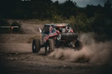 An off-road vehicle kicking up dust on a rugged trail in the countryside.