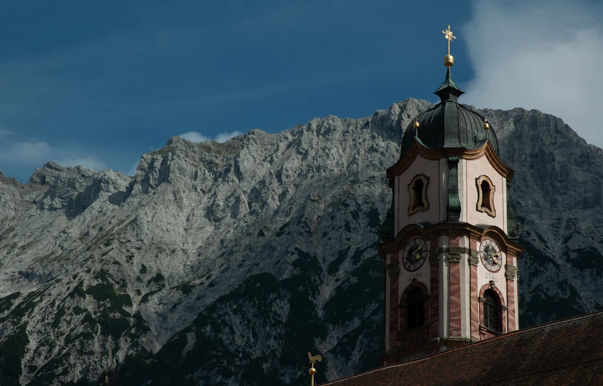 The painted church tower of Mittenwald against the grey cliffs of the Karwendel