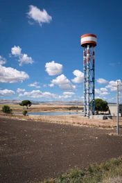 A sturdy water tower standing tall on a rural construction site under a clear sky.