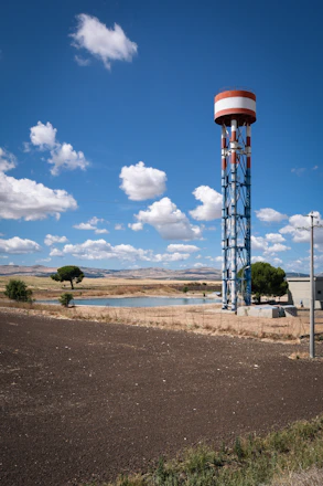 A sturdy water tower standing tall on a rural construction site under a clear sky.