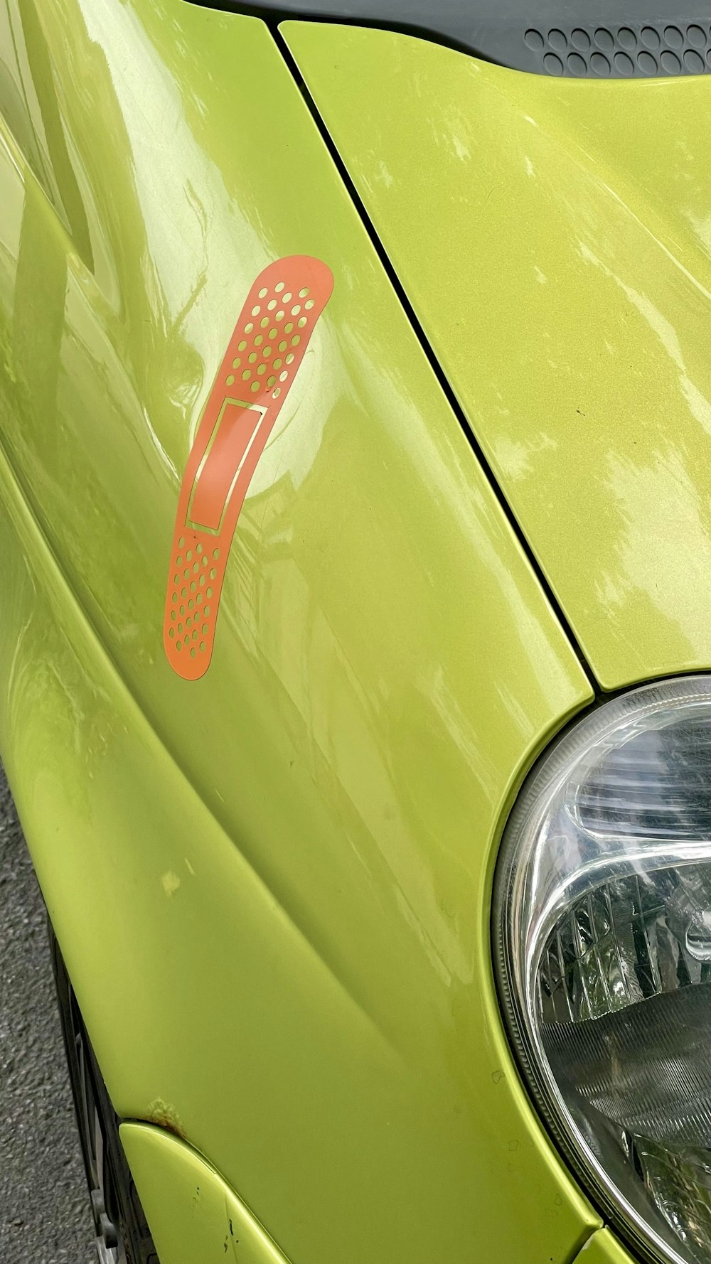 a close up of a green car with a red sticker on it