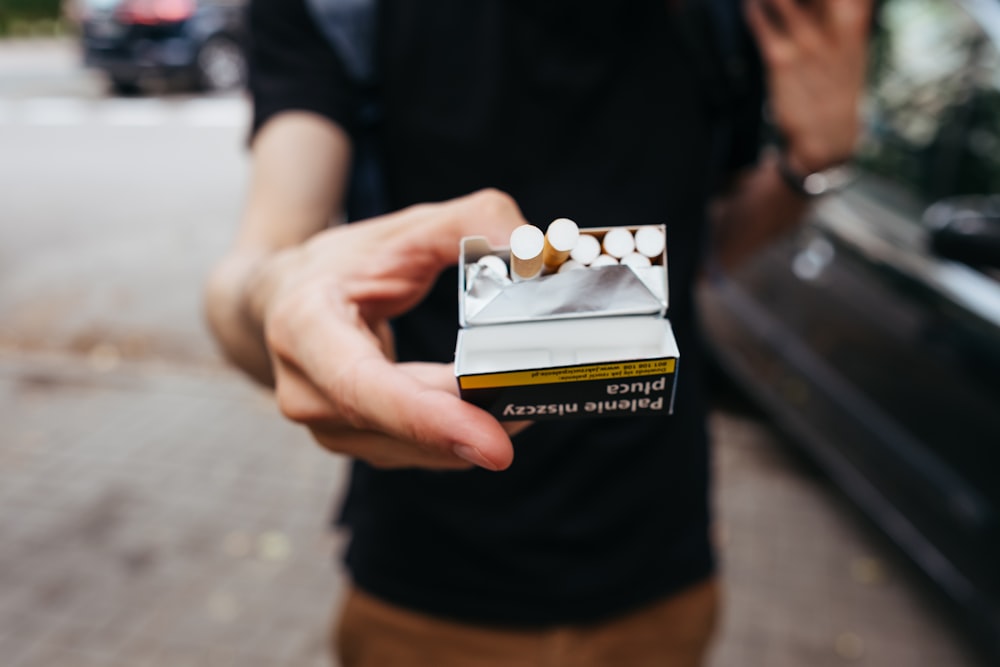 Un hombre sosteniendo un cigarrillo en la mano