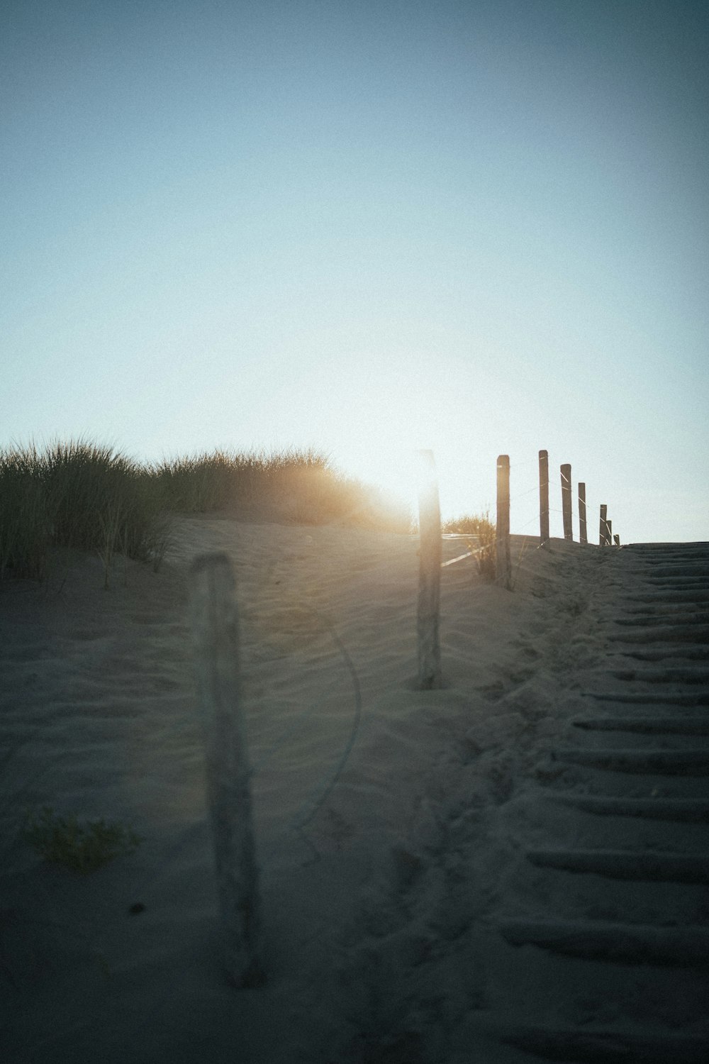 the sun is setting on a sandy beach