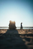 A beach scene at sunset with a stylish backpack and neck pillow set beside a gently crashing wave.