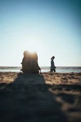 A serene beach sunset with a lone traveler planning their next adventure on a laptop.