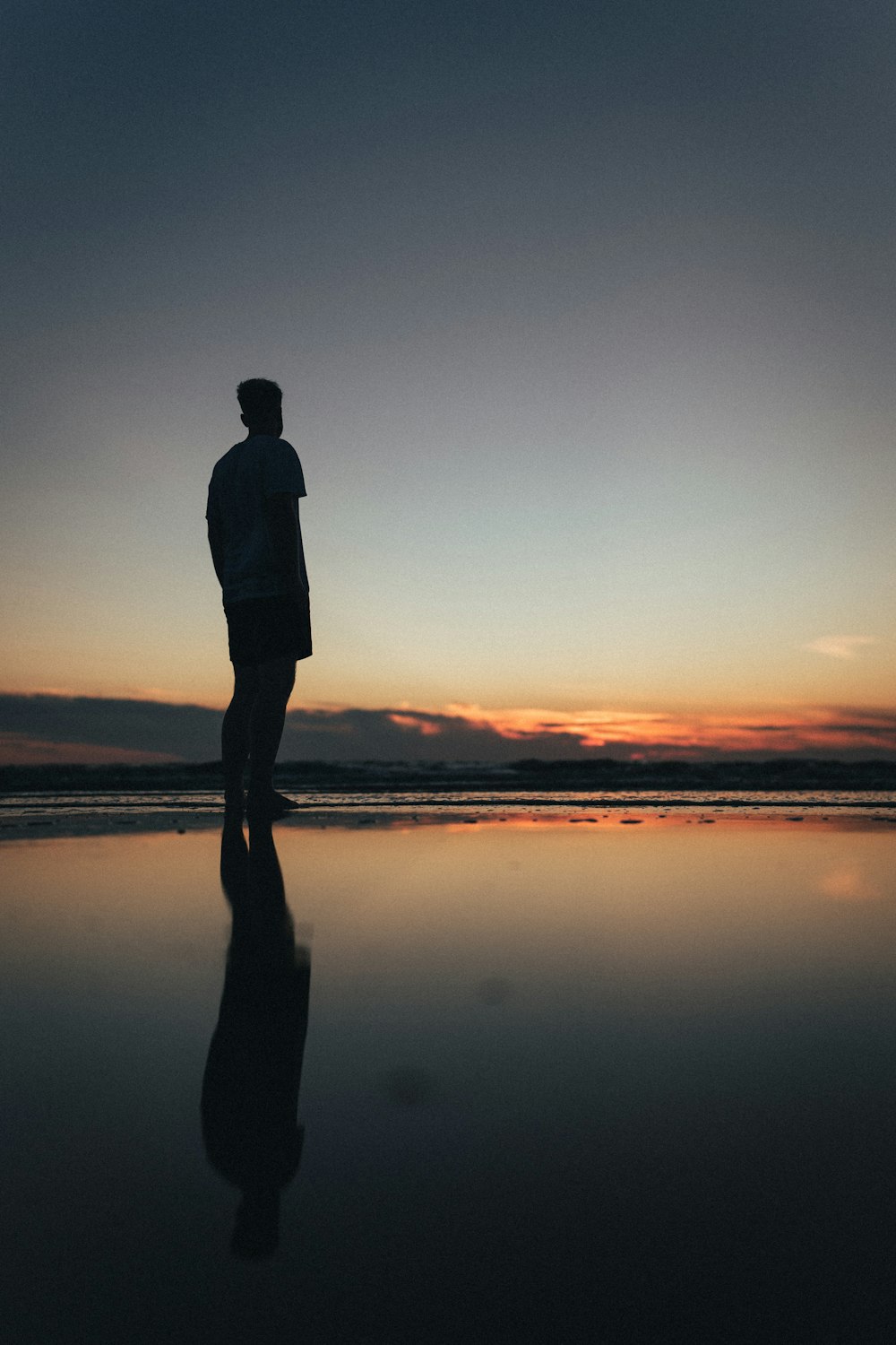 a man standing on a beach at sunset