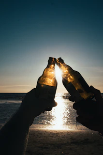 Sunset at the beach with friends raising their Pilsen do Verão glasses in a toast