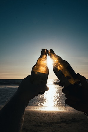 Friends sharing a laugh and water bottles after a sunset run along the beach.