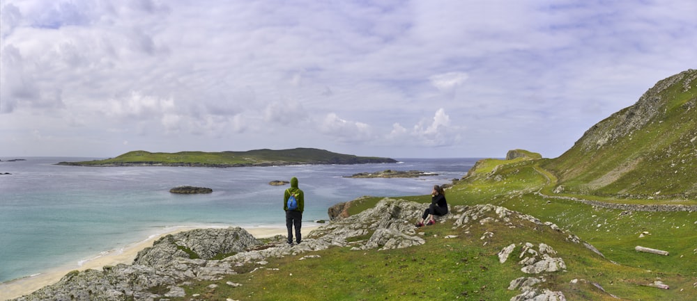 a couple of people standing on top of a lush green hillside