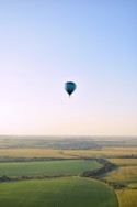 a hot air balloon flying over a green field