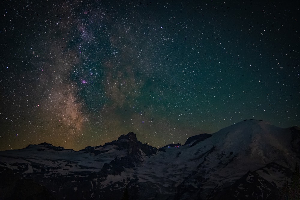 the night sky with stars above a mountain range