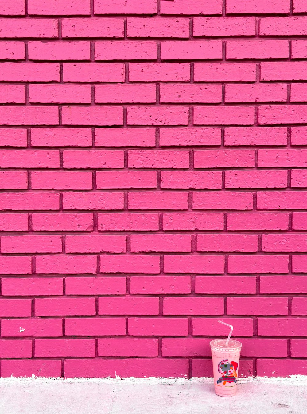 a pink brick wall with a drink in front of it