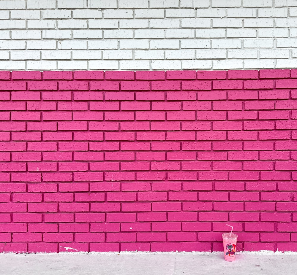 una pared de ladrillo rosa con una bebida frente a ella