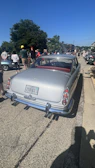 Crowd admiring a vintage car at an outdoor automobile show.