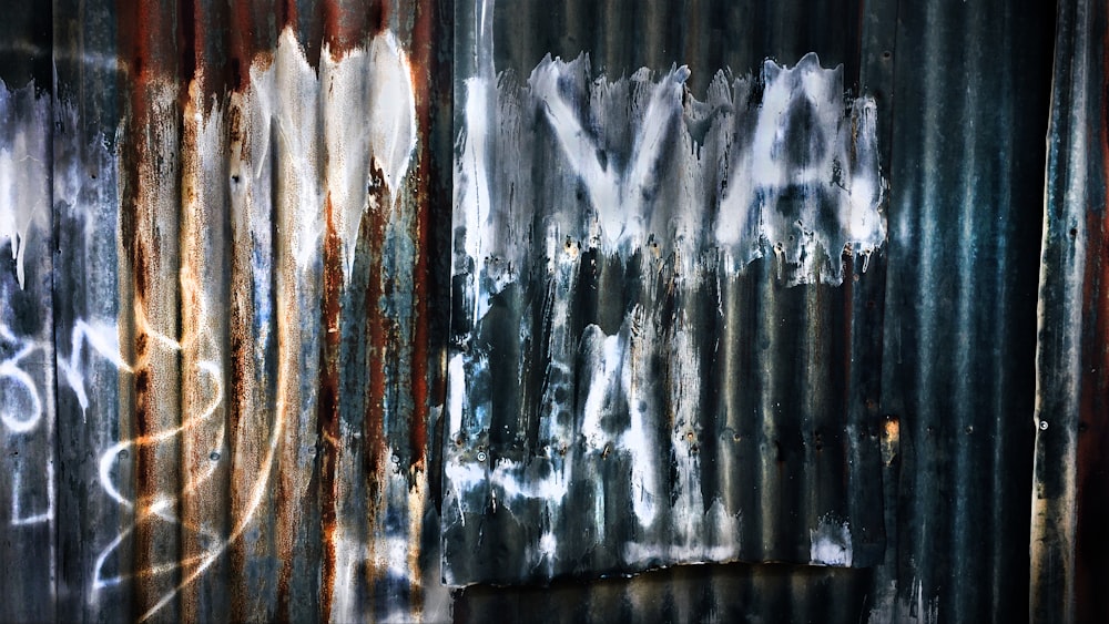 a rusted metal wall with graffiti on it