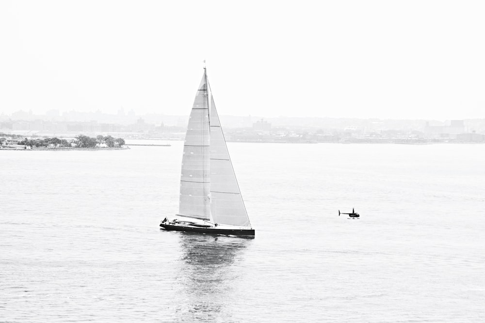 a sailboat in a body of water with a city in the background