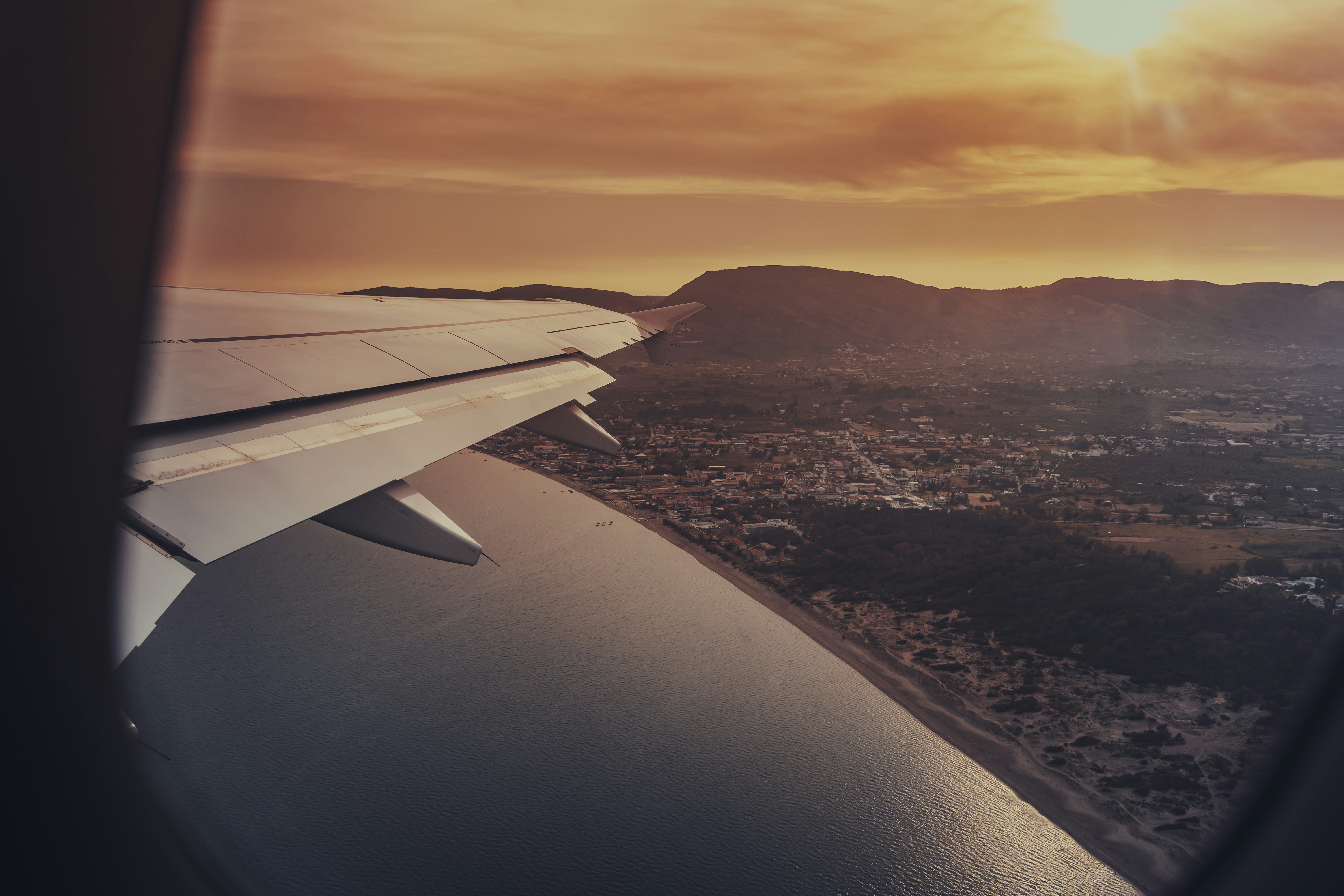 a view of the wing of an airplane as it flies over a city, 