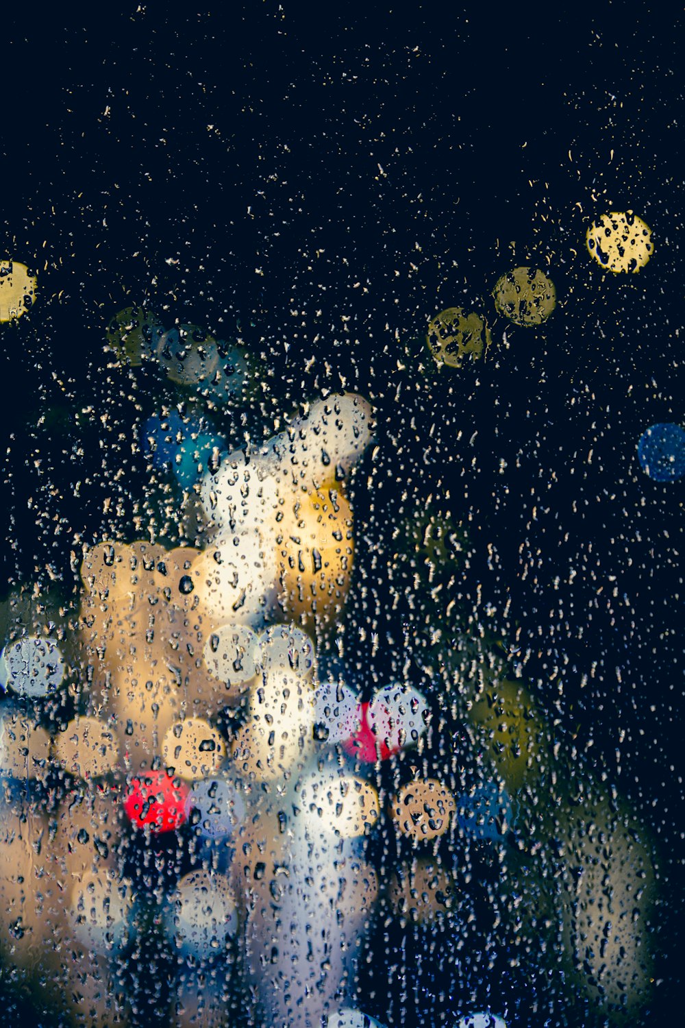 rain drops on a window with a blurry image of a city street