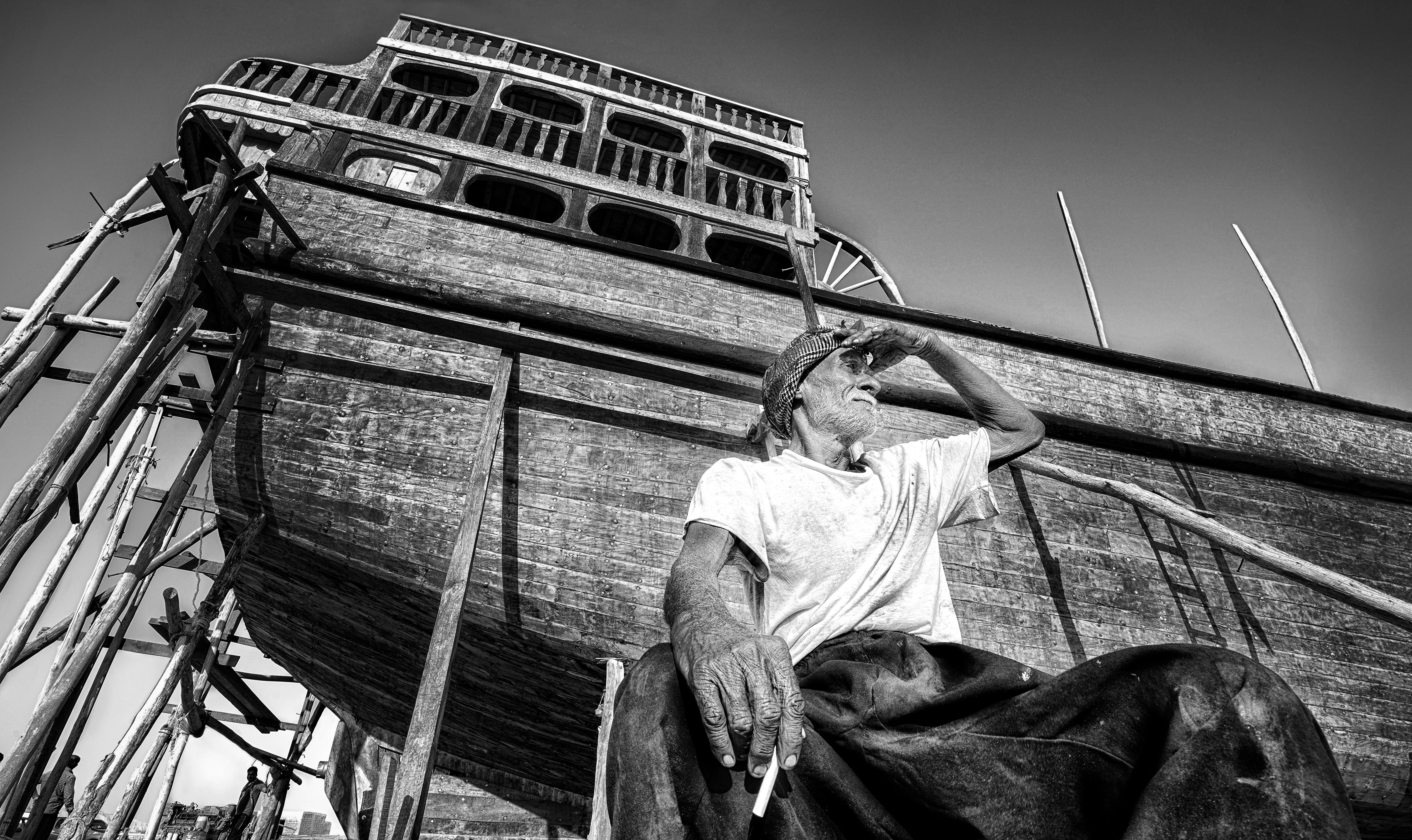 a black and white photo of a man sitting on a boat