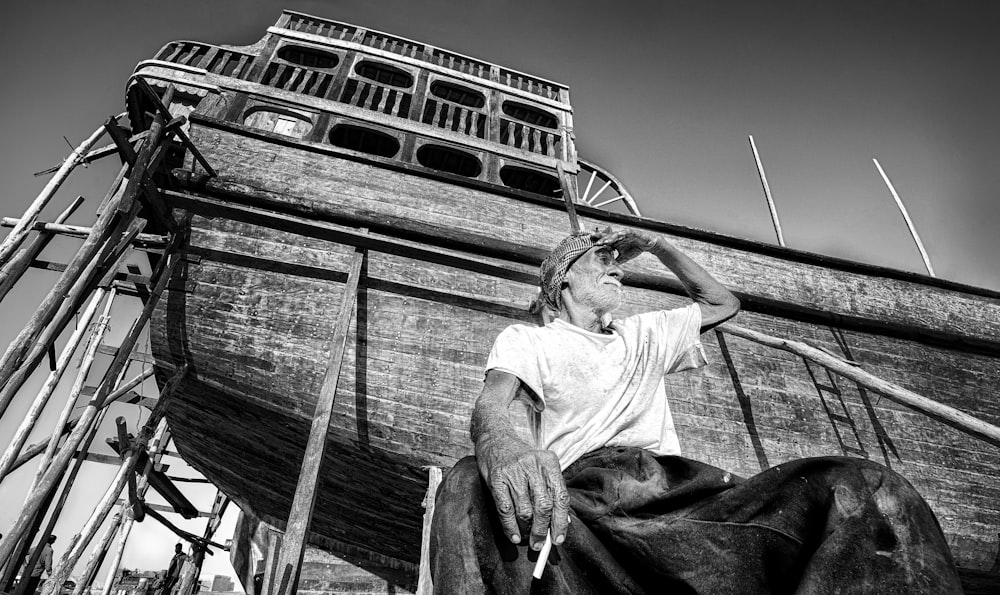 a black and white photo of a man sitting on a boat