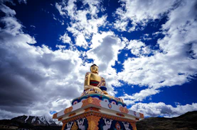 a golden buddha statue sitting on top of a hill
