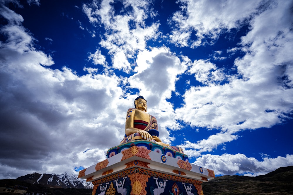 a golden buddha statue sitting on top of a hill