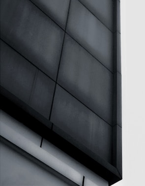 Modern commercial building facade featuring dark grey cladding and clean geometric shapes.