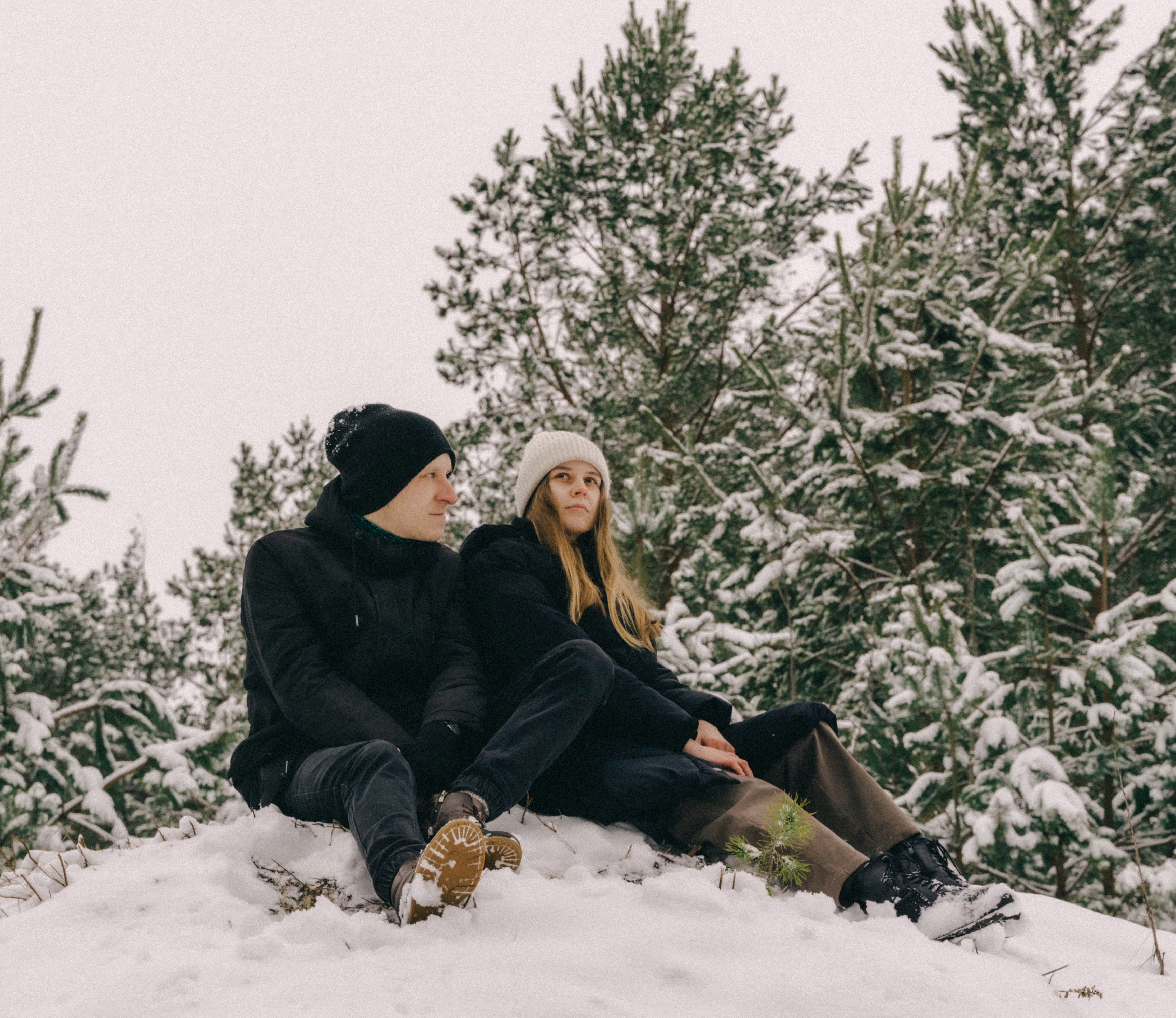 a couple of people sitting on top of a snow covered ground