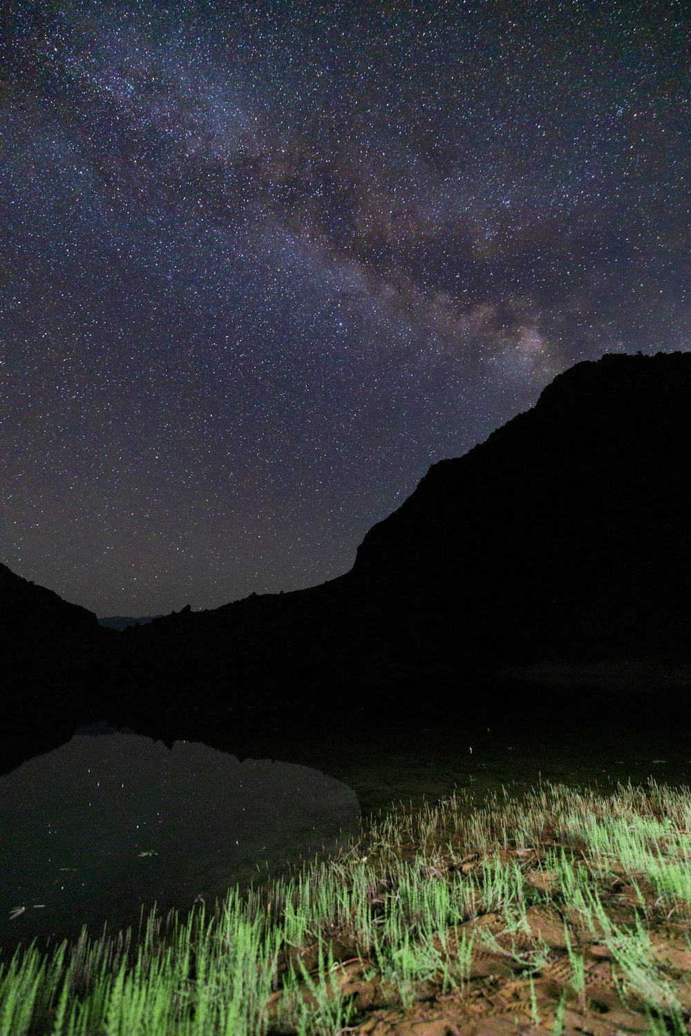 the night sky is filled with stars above a lake