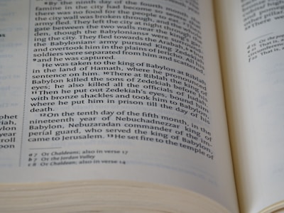 An open book displaying a page with two columns of text, written in a formal, structured format typical of biblical or historical documents. The text includes references to historical events and figures. The edges of the pages are slightly curled, indicating use.