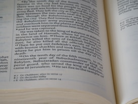 An open book displaying a page with two columns of text, written in a formal, structured format typical of biblical or historical documents. The text includes references to historical events and figures. The edges of the pages are slightly curled, indicating use.