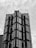 A high-rise building with a modern architectural design features a series of glass panes and sharp geometric shapes. The structure appears to have multiple protruding sections with reflective surfaces, creating a pattern of lines and angles.
