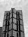 A high-rise building with a modern architectural design features a series of glass panes and sharp geometric shapes. The structure appears to have multiple protruding sections with reflective surfaces, creating a pattern of lines and angles.