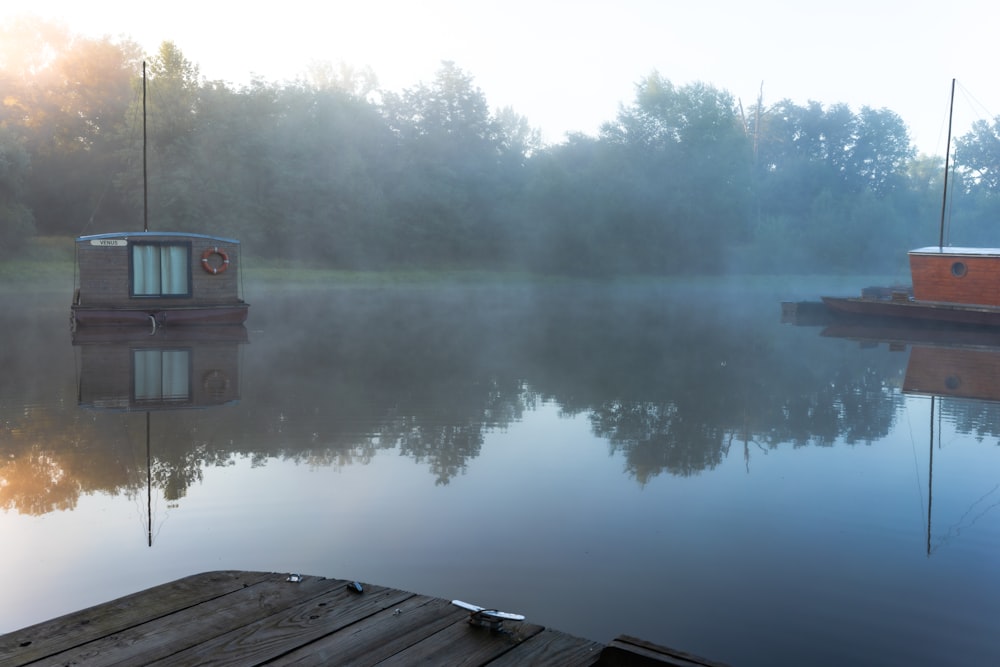 a small boat floating on top of a lake next to a dock