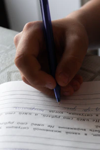Close-up of a hand writing on legal contract forms with a blue pen.