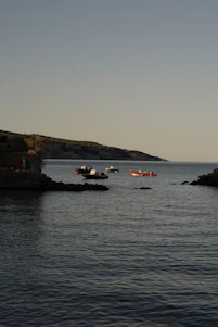 A serene early morning scene of electric boats gliding silently across a calm Mediterranean bay.