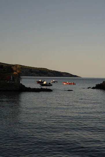 A serene early morning scene of electric boats gliding silently across a calm Mediterranean bay.