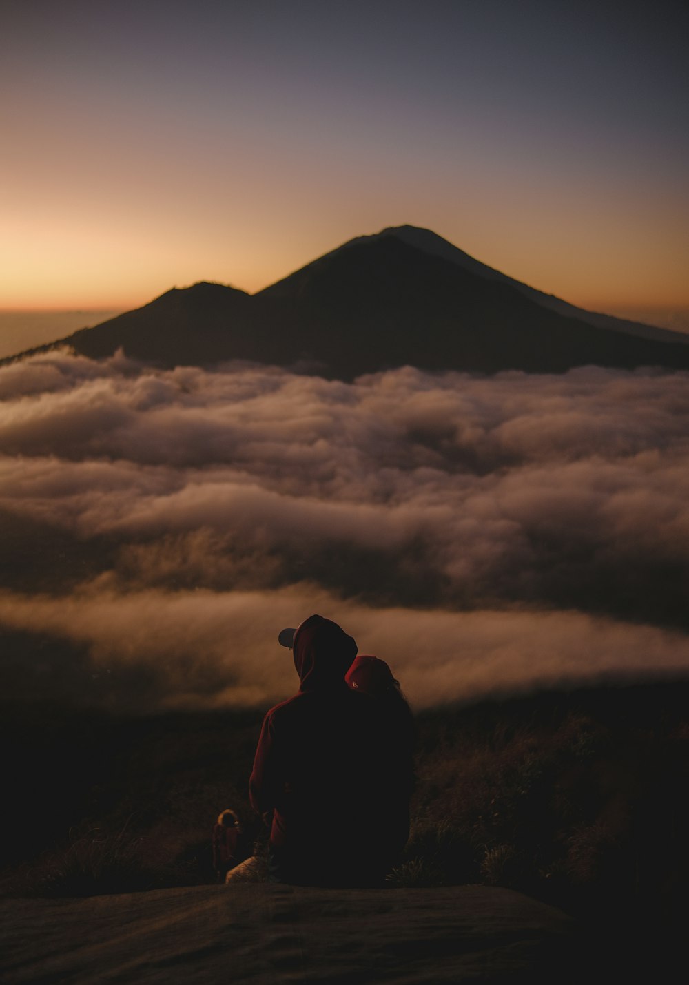 a person sitting on top of a mountain with a view of the clouds