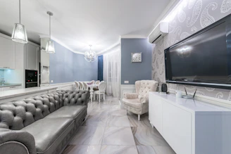 A beautifully designed living room showcasing a sleek false ceiling and a modern modular kitchen.