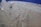 Peeling paint on a textured wall reveals an underlying layer beneath. The upper portion features a rough patch of blue paint, while the beige surface below is cracked and flaking.